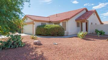 Set amidst lush gardens, this single-story home features a red-tiled roof and a cozy entryway.