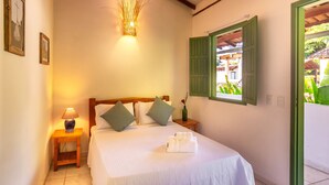 A neatly made bed with pillows, a bedside lamp, and a wall-mounted light fixture. - Pousada Verde Mar (Porto Seguro)