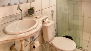 A bathroom with a white sink, toilet, and glass shower enclosure. - Pousada Verde Mar (Porto Seguro)