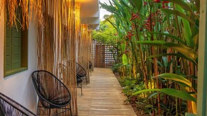 A wooden pathway flanked by chairs and plants, leading to a building entrance. - Pousada Verde Mar (Porto Seguro)
