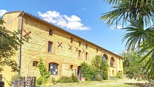 Un edificio in mattoni di due piani, con finestre ad arco e tetto piatto.