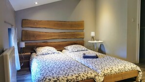 Camera da letto con un letto grande, una testata in legno, comodini e un piccolo tavolino con una lampada.