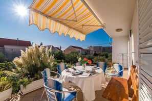 Un patio al aire libre con una mesa redonda, sillas y un toldo a rayas.