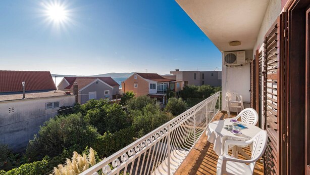 Ein Balkon mit Blick auf Häuser, einem Tisch mit Stühlen und einer Klimaanlage.