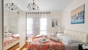 Ein Schlafzimmer mit einem Bett, einem Nachttisch, einem Spiegel, einem Gemälde und einer Deckenleuchte.