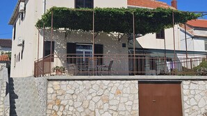 Une maison à deux étages avec une façade en pierre, un toit en tuiles et une porte marron.