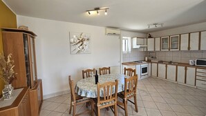 Une cuisine spacieuse avec un coin repas, comprenant un meuble en bois, une table avec des chaises et un tableau accroché au mur.