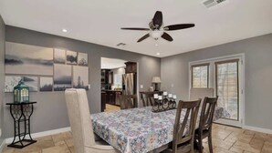 A dining area with a table set for four, a ceiling fan, and artwork on the walls. - Renovated Retreat | Spa + Sauna | Near Downtown (Prescott)