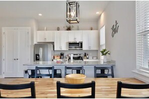 Enjoy cooking in the well-equipped kitchen with a central island, stainless steel range hood, and dining area with a wooden table.