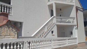 Un bâtiment à deux étages, avec une façade blanche, un socle en pierre et un toit recouvert de tuiles rouges.