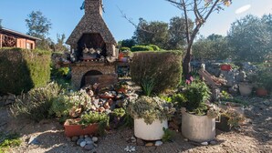 A garden with a stone-built outdoor oven, various potted plants, and a rustic wooden structure. - Holiday Home Stella - cozy studio (Zaton)