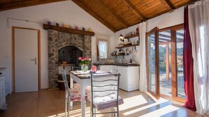 A dining area with a stone fireplace, wooden ceiling, and a view through glass doors. - Holiday Home Stella - cozy studio (Zaton)