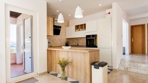 A modern kitchen with a central island, white cabinetry, and pendant lighting.