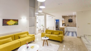 A modern living room with a yellow sofa set, a white coffee table, and a painting on the wall.