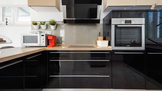 A modern kitchen with black cabinets, a Bosch oven, a microwave, and a coffee machine.