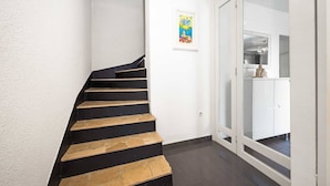 A staircase with alternating black and beige steps leading to a white door with glass panels.