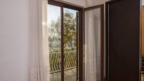 Una habitación con puerta de vidrio corredera que da a un balcón con baranda metálica.