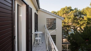 A balcony with a white table and two chairs, a window, and a door with a dark shutter. - Apartments Gaj Brodarica - A9 (Šibenik-Brodarica)