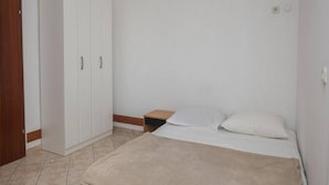 A bedroom with a bed, a wooden nightstand, and a white wardrobe. - Apartments Gaj Brodarica - A9 (Šibenik-Brodarica)