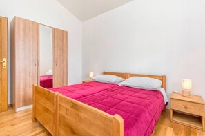 Une chambre à coucher avec un lit en bois, une table de chevet, une armoire et un miroir.