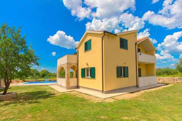 Une maison à deux étages dotée d’une piscine, d’une arche en pierre et d’un mur en pierre.