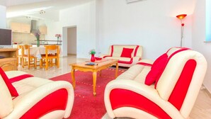A modern living room with a red and white sofa set, a wooden coffee table, and a dining area in the background.