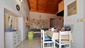 Un comedor acogedor con pared de piedra, techo de madera y mesa preparada para dos.