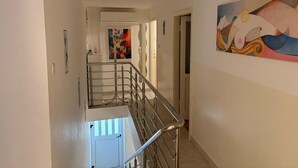 A hallway with a staircase, a door at the end, and a colorful abstract painting on the wall. - Stone Apartment Primosten (Primošten)