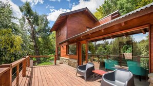 A wooden cabin with a deck, outdoor seating, and large windows. - Solar Selvana - Casas de montaña (Villa La Angostura)