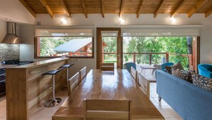 A spacious kitchen with wooden beams, a bar area, and a large dining table. - Solar Selvana - Casas de montaña (Villa La Angostura)