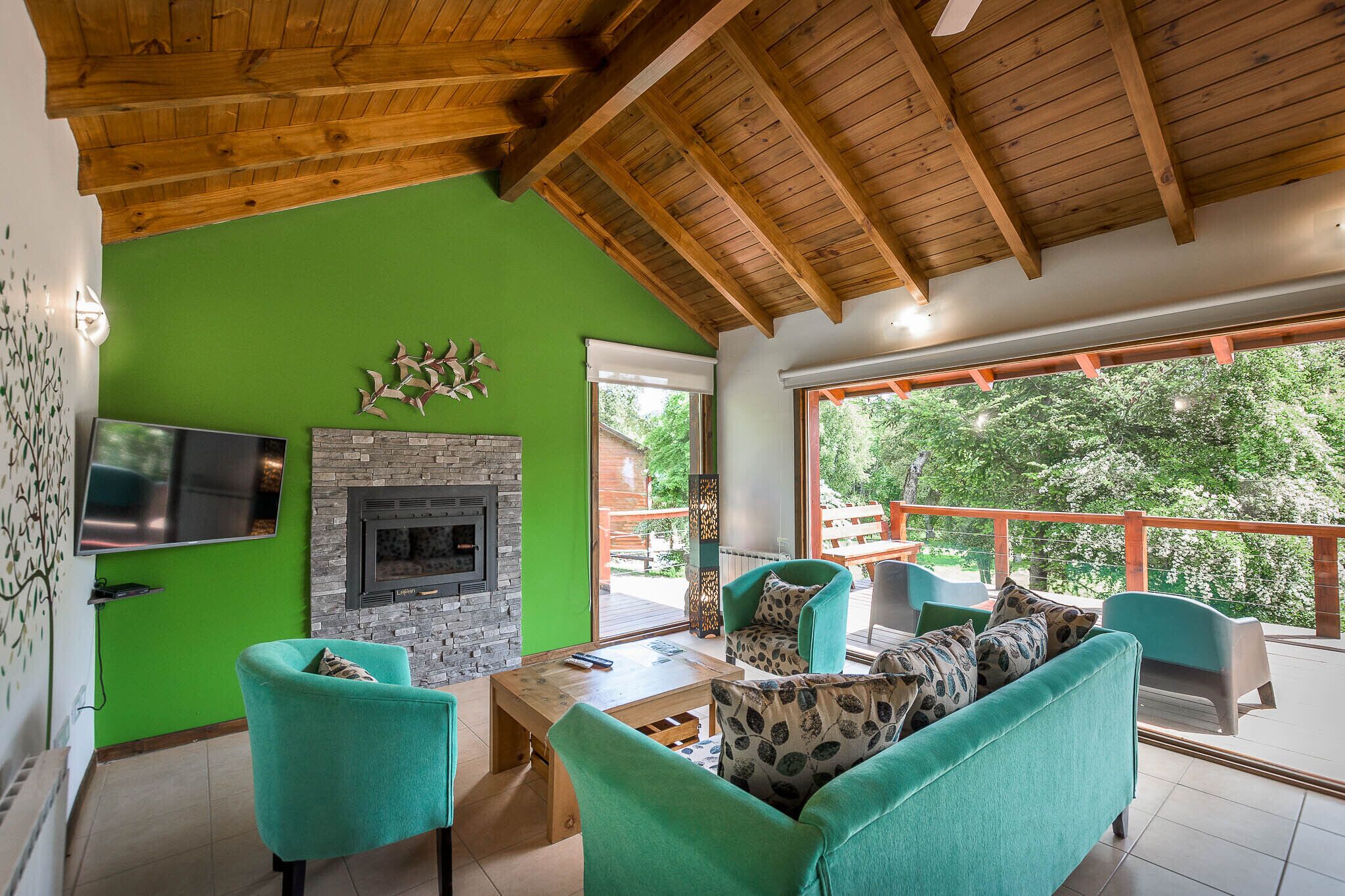 A living room with green walls, a fireplace, and a large window overlooking a deck.