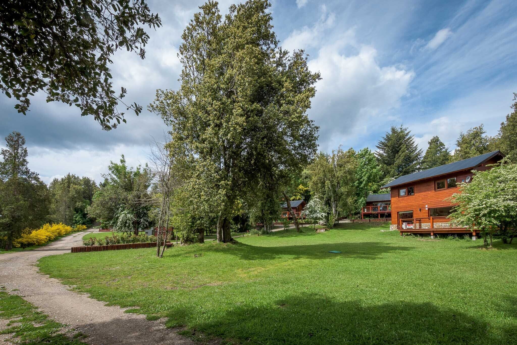 A residential property with a large lawn, a wooden deck, and a house with a red roof.
