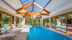 A modern indoor swimming pool with a skylight, sun loungers, and large glass doors. - Solar Selvana - Casas de montaña (Villa La Angostura)