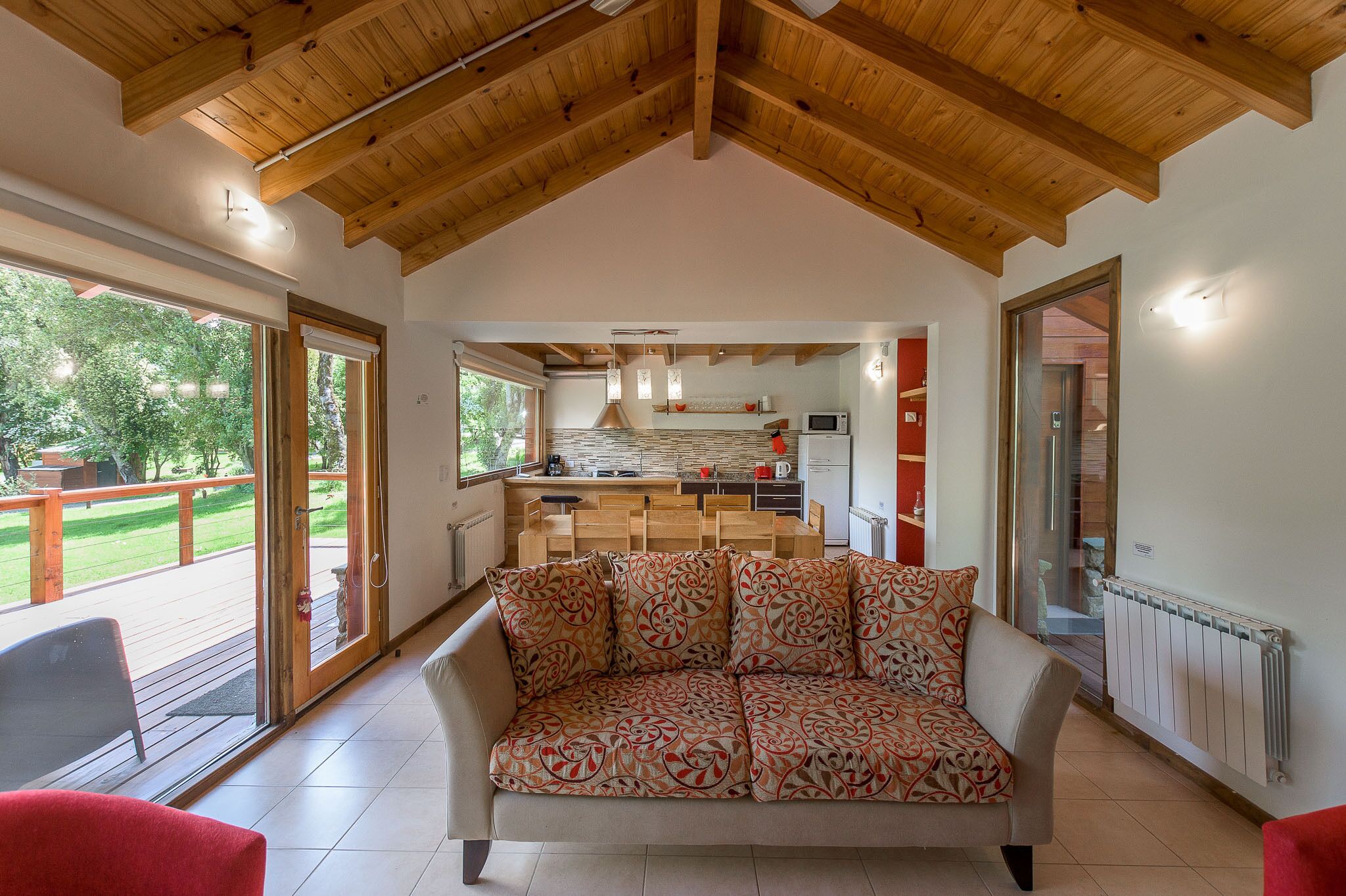 Una sala de estar acogedora con un sofá, un comedor con mesas de madera y una cocina con electrodomésticos modernos.
