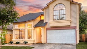 Une maison à deux étages avec un garage, de grandes fenêtres et une pelouse bien entretenue.