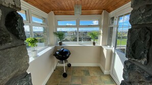 A room with a stone wall, a wooden ceiling, and a view of a rural landscape through large windows. - Traditional Welsh cottage in the village of Dyffryn Ardudwy (Dyffryn Ardudwy)