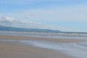 A beach with a wide sandy shore and gentle waves.