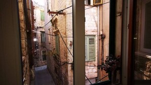 A narrow street view through a window with a candle on the sill.