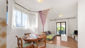 A living room with a dining table, chairs, a sofa, and a TV.