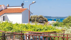 A white building with a red-tiled roof, a security camera, and a metal railing in the foreground.