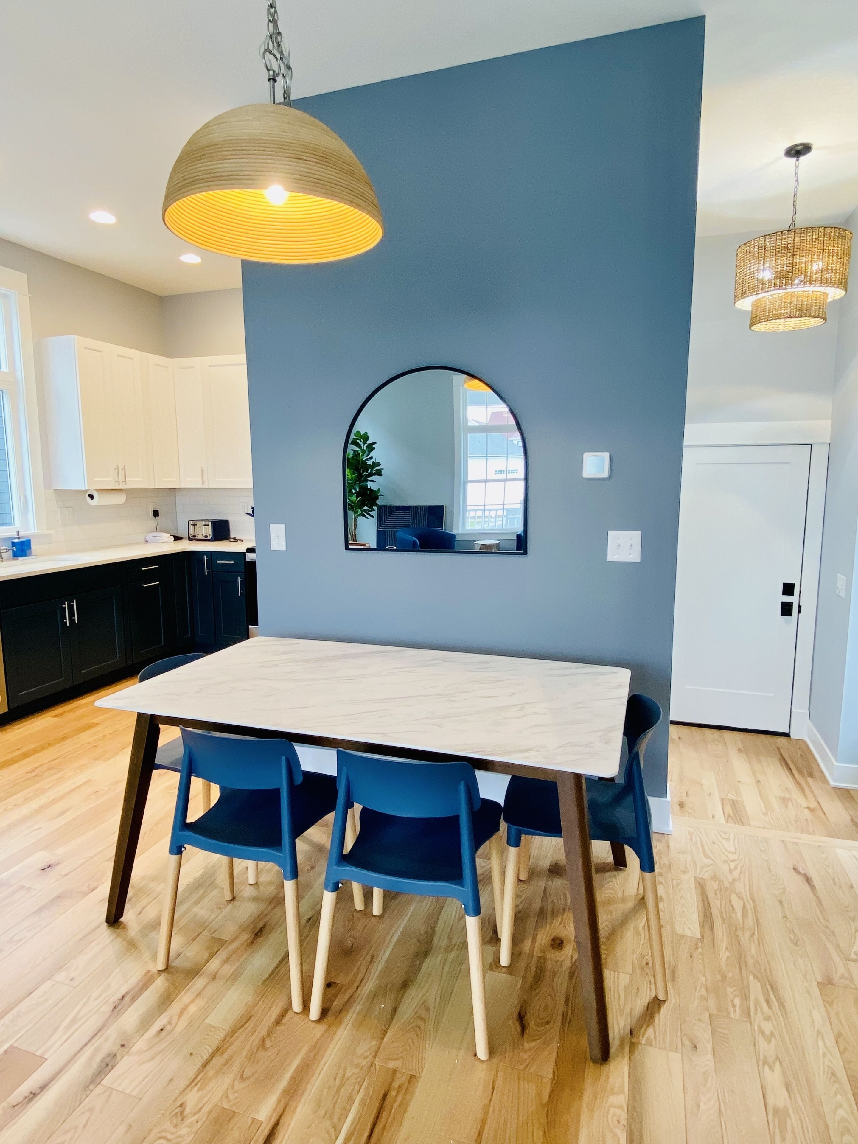 A modern kitchen with white cabinets, a wooden dining table, and blue chairs.