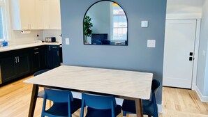 Una cocina moderna con armarios blancos, una mesa de comedor de madera y sillas azules.