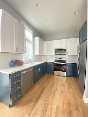 A modern kitchen with white cabinets, a stainless steel refrigerator, and a built-in oven.