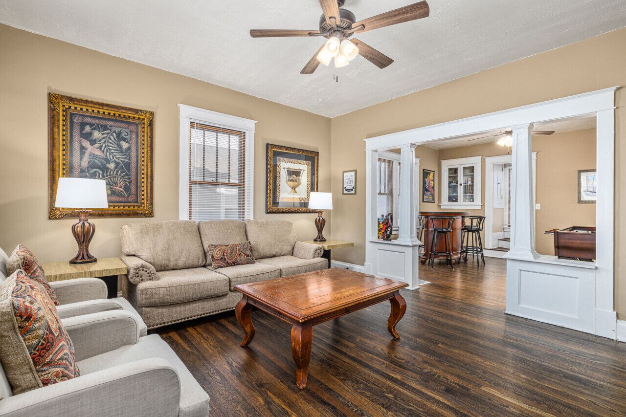 A living room with a sofa, armchairs, a wooden coffee table, and a ceiling fan.