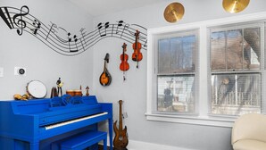 Una habitación con un piano azul, varios instrumentos de cuerda y una pared decorada con notas musicales.
