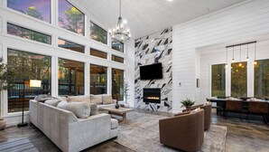 A spacious living room with a fireplace, large windows, and a modern TV.