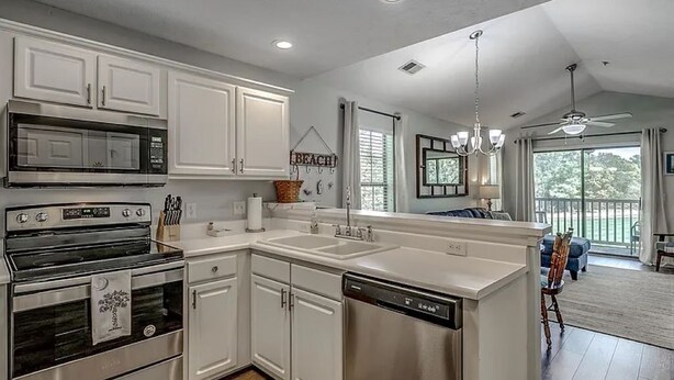 A modern kitchen with white cabinetry, stainless steel appliances, and a large island.
