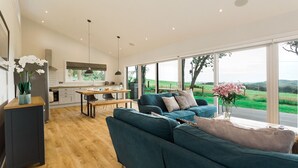 Un salon moderne doté d’une grande fenêtre, d’un canapé et d’un coin repas avec une table et des chaises.