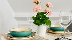 A dining table with teal and gold plates, a clear wine glass, and pink flowers in a white vase. - Stunning Top Floor Flat | Pet Friendly | Sea Views (Torquay)