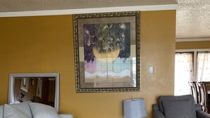 A living room with two grey sofas, a large abstract painting, a lamp, and a patterned carpet.